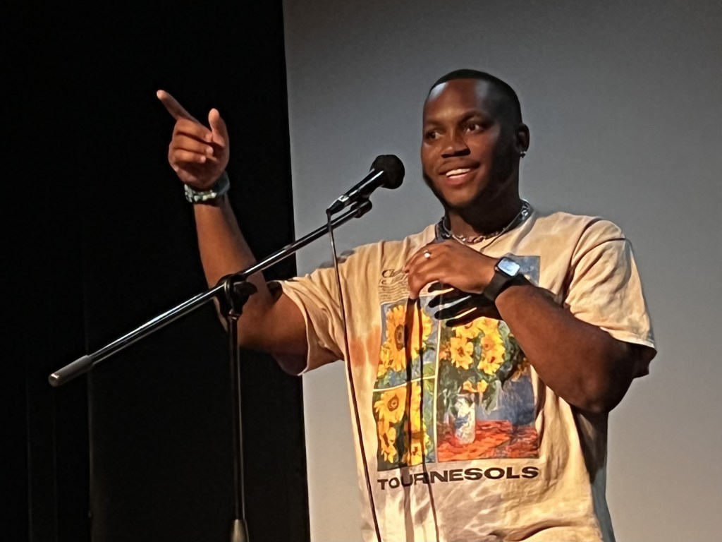 standing at a microphone, doing spoken word