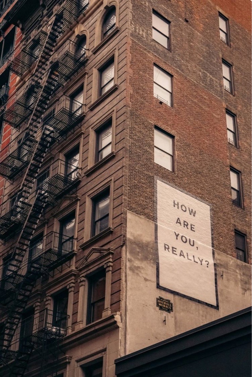 a poster reads "how are you really" on the side of a building